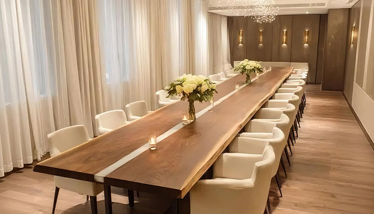 Long wooden table with chairs in a modern room with curtains and wall lights.