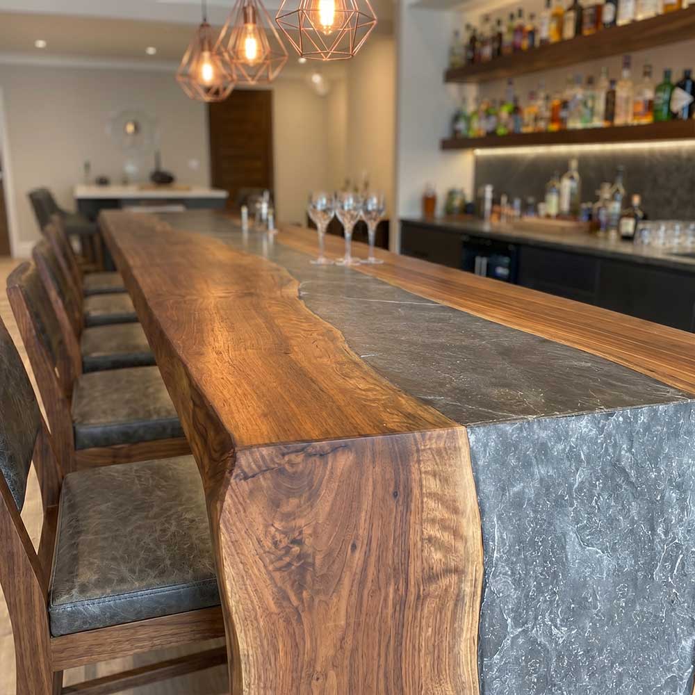 Wooden bar counter with gray stone finish in a modern bar setting.