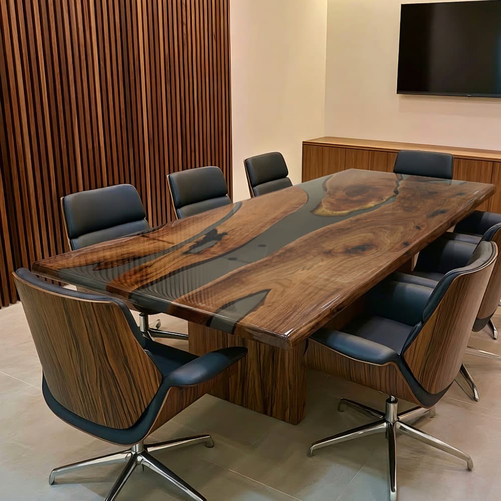 Custom long walnut resin office table in a corporate conference room with wood slat accent wall and media screen