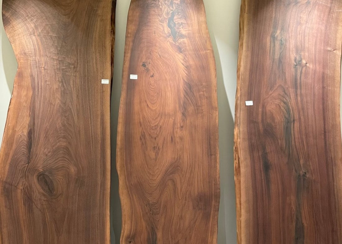 Natural live-edge walnut wood slabs stacked outdoors, ready for epoxy table production