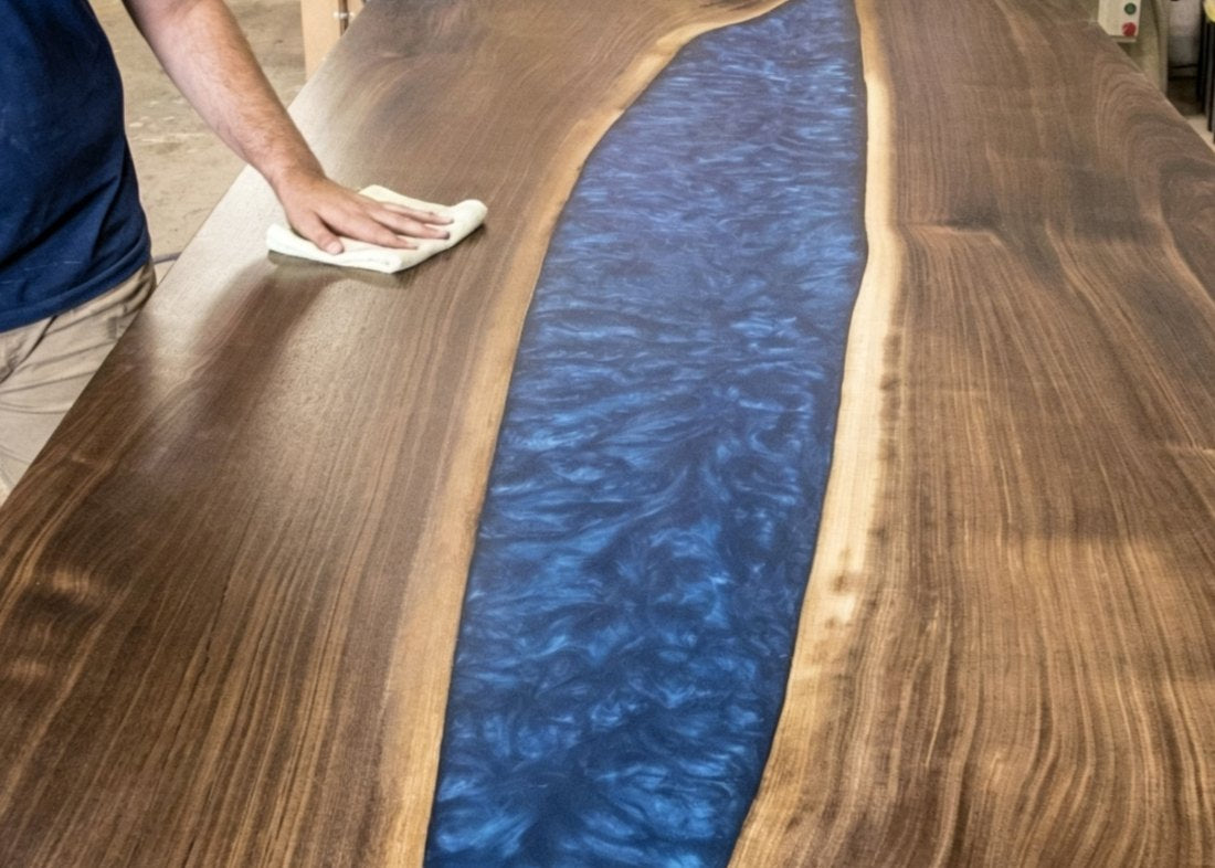 Close-up of a fully polished, glossy epoxy river table with a clear blue river design